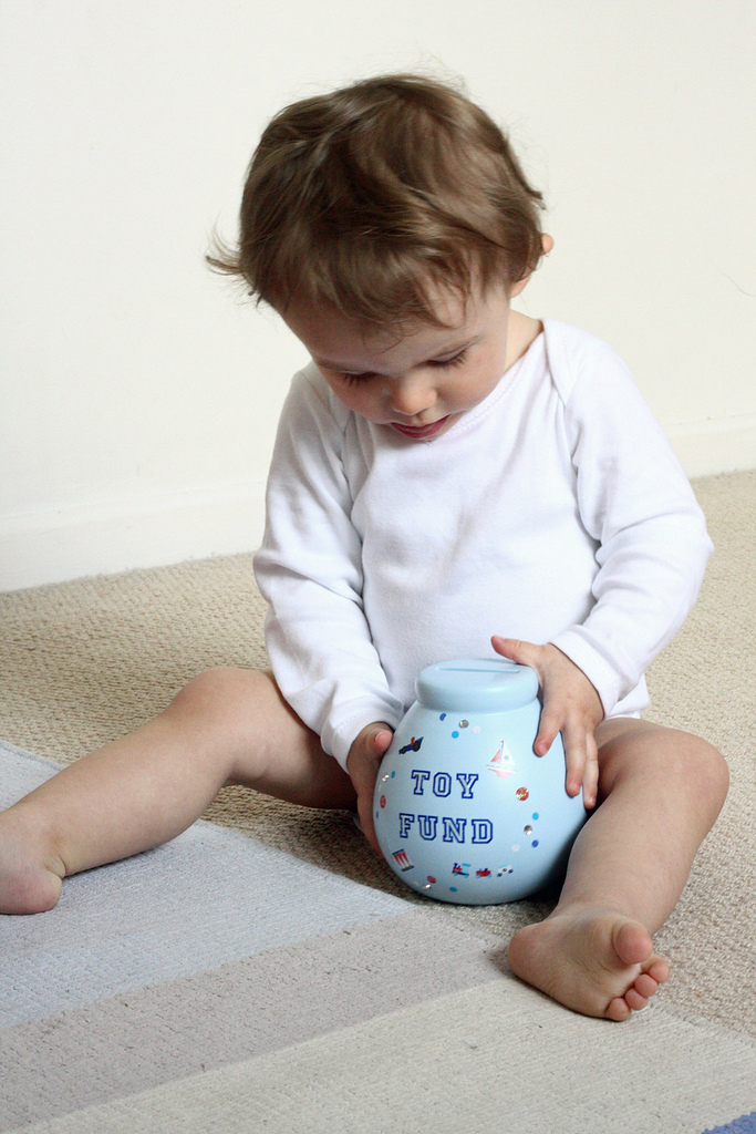 A young child learning to save as she examines a piggy bank.